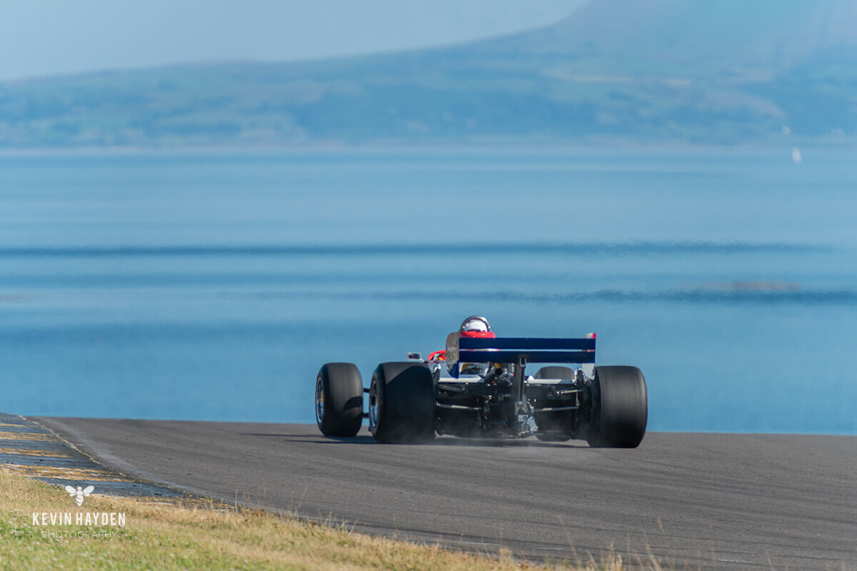 The 1981 F1 Ensign driven by Michael Lyons disappearing into the Welsh mountains and Irish Sea on Trac Mon, Anglesey. Photo by Kevin Hayden.